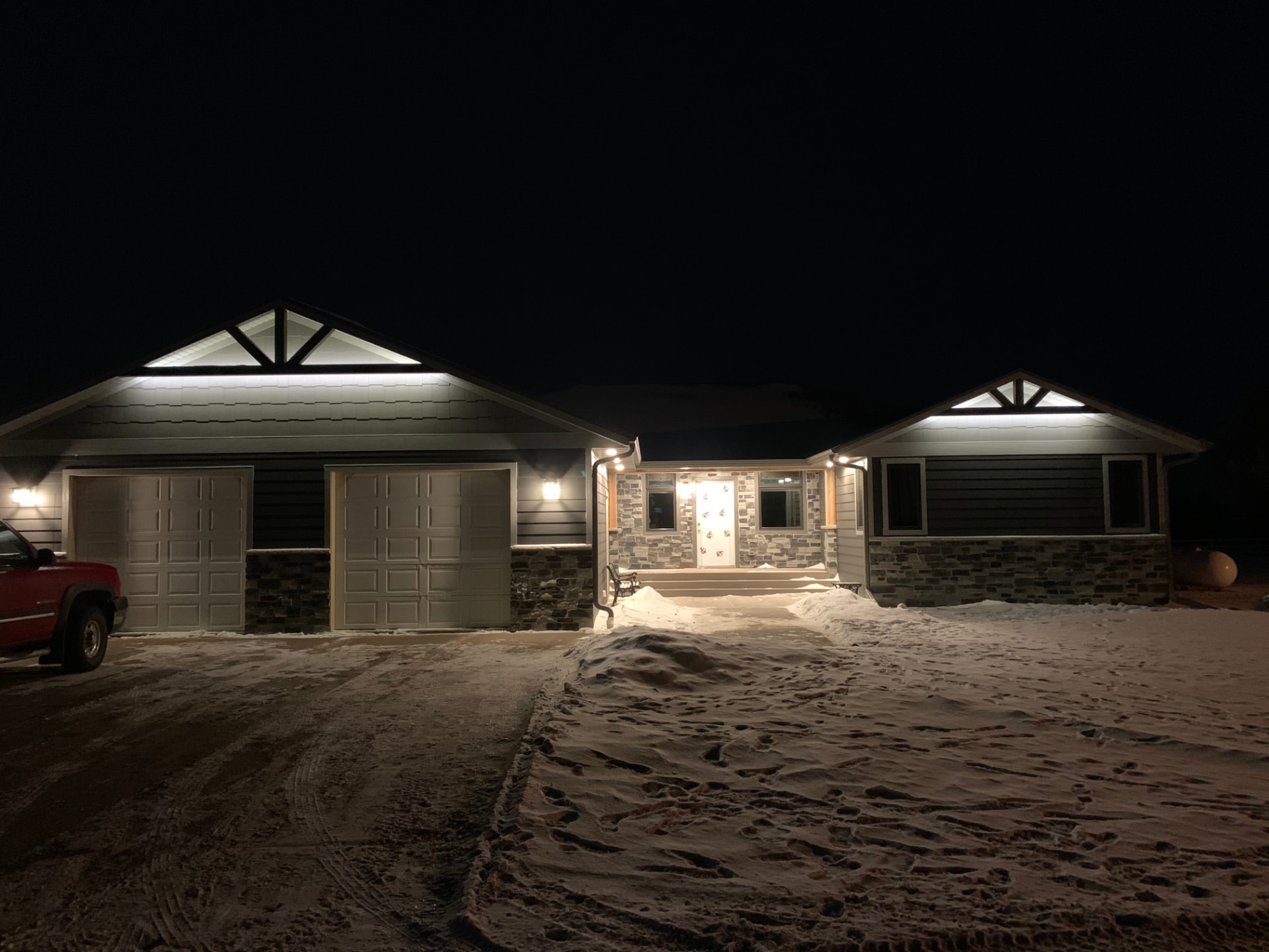 Exterior lighting on a home with closed garage doors at night