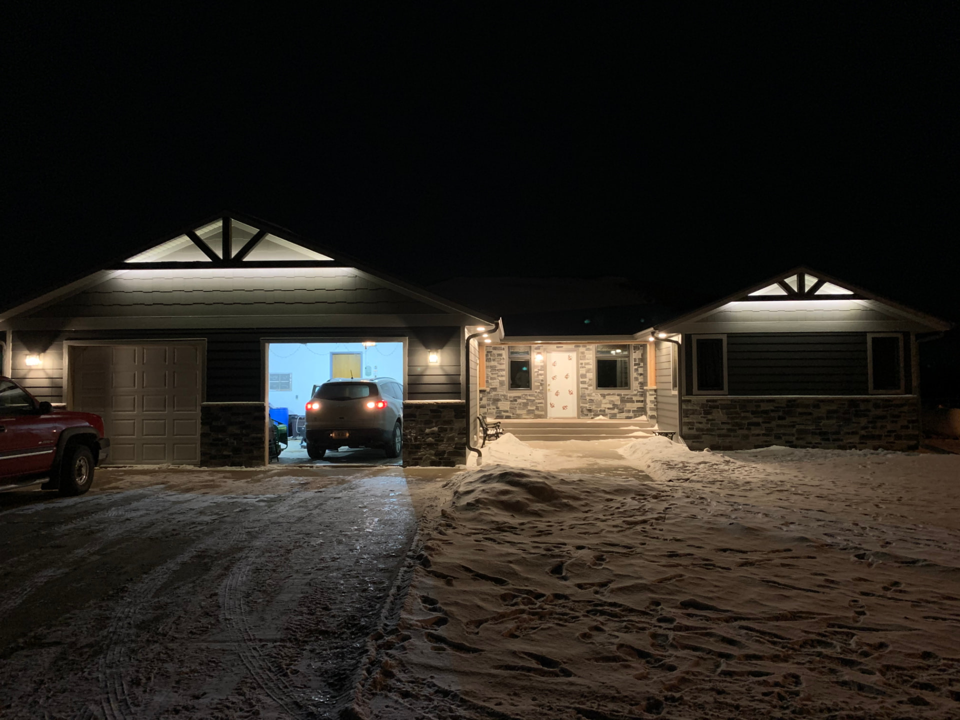 Home exterior lighting at night with an open garage